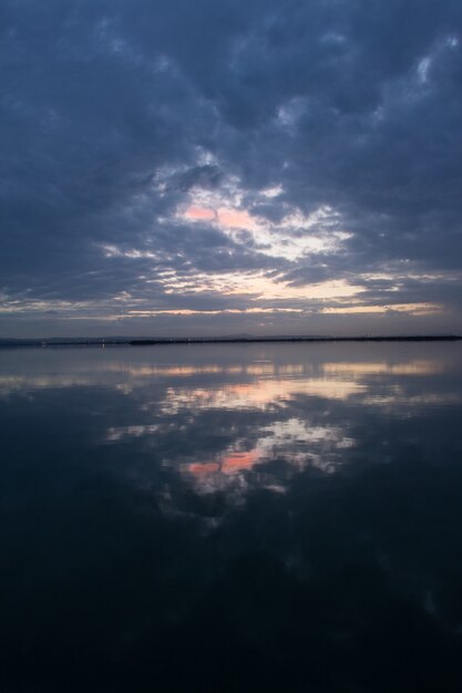 Impresionante paisaje del cielo del atardecer con nubes de tormenta que se reflejan en la superficie del agua