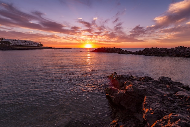 Impresionante paisaje de la hermosa puesta de sol y el colorido cielo nublado reflejado en el mar