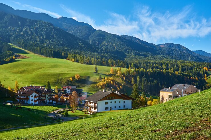 Foto gratuito impresionante paisaje otoñal en el pueblo de santa maddalena con árboles coloridos de la iglesia y prados bajo los rayos del sol naciente alpes dolomitas italia