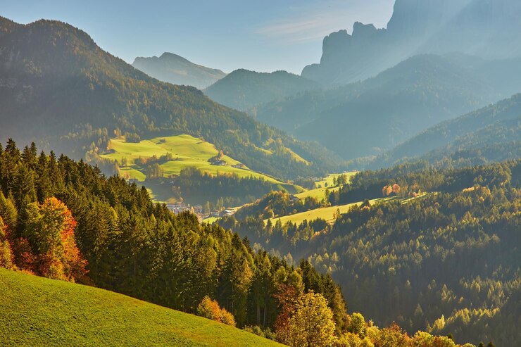 Foto gratuito impresionante paisaje otoñal en el pueblo de santa maddalena con árboles coloridos de la iglesia y prados bajo los rayos del sol naciente alpes dolomitas italia