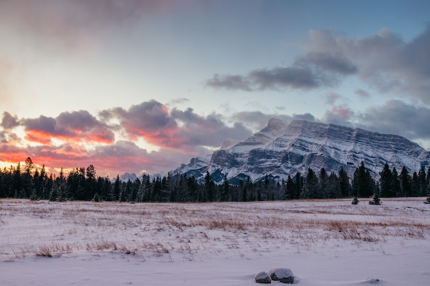 Foto gratuita impresionante paisaje de un paisaje montañoso cubierto de nieve bajo el hermoso cielo del atardecer