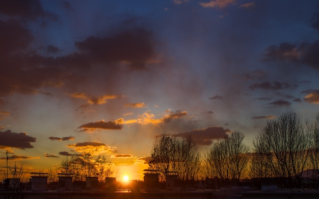 Impresionante paisaje de la puesta de sol en el cielo nublado y siluetas de árboles en Zagreb, Croacia.