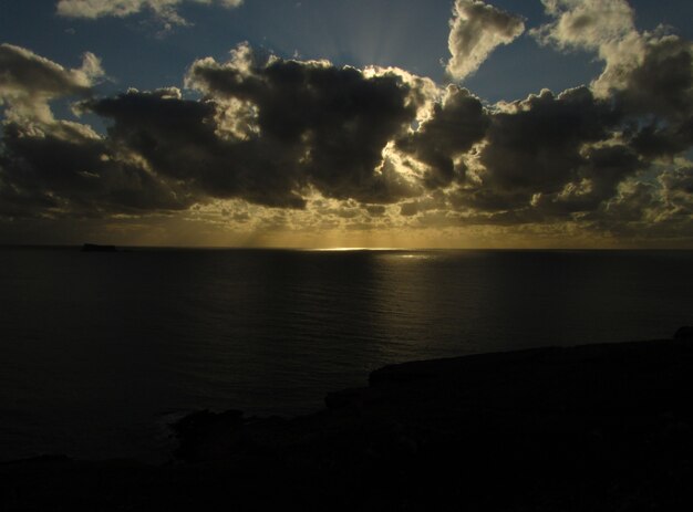 Impresionante puesta de sol sobre el océano con el islote de Filfla en Malta en un día nublado