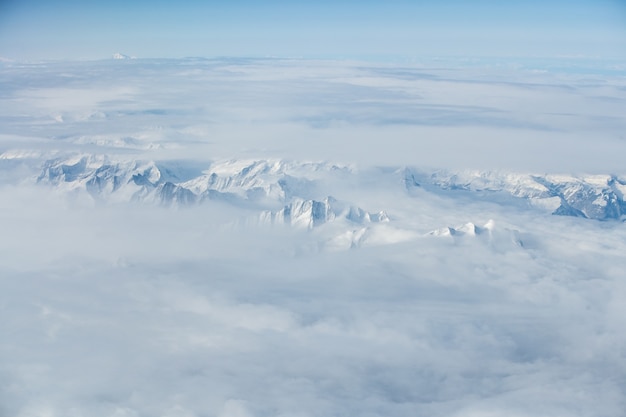 Impresionante toma aérea de las cimas nevadas cubiertas de nubes