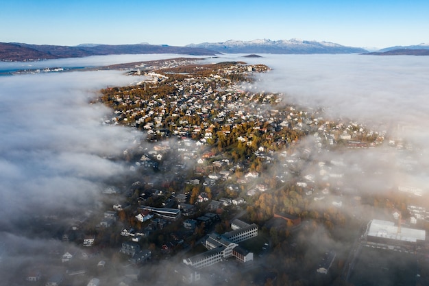 Impresionante toma aérea del paisaje urbano rodeado de árboles verdes bajo un cielo escénico nublado