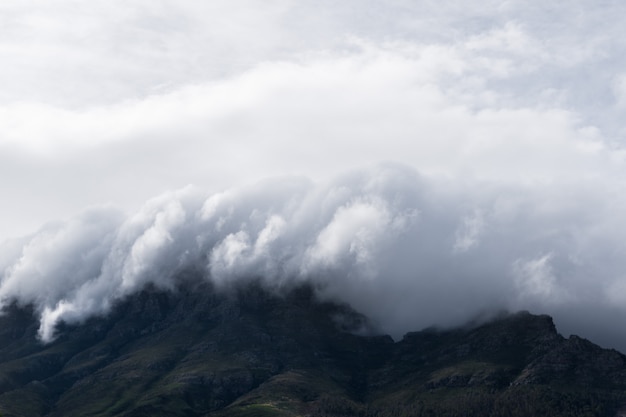 Impresionante toma de las nubes blancas que cubren las colinas oscuras