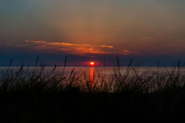 Impresionante toma de la puesta de sol sobre la orilla del océano en Vrouwenpolder, Zelanda, Países Bajos