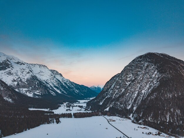 Impresionante vista de una cordillera en un día frío y nevado durante la puesta de sol