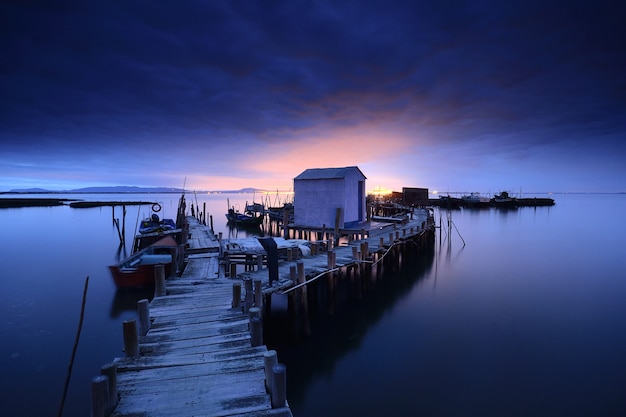 Impresionante vista de un muelle de madera y una cabaña sobre el océano tranquilo en el crepúsculo