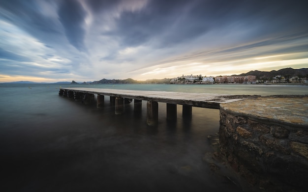 Impresionante vista del paisaje marino con un muelle de madera en la espectacular puesta de sol escénica