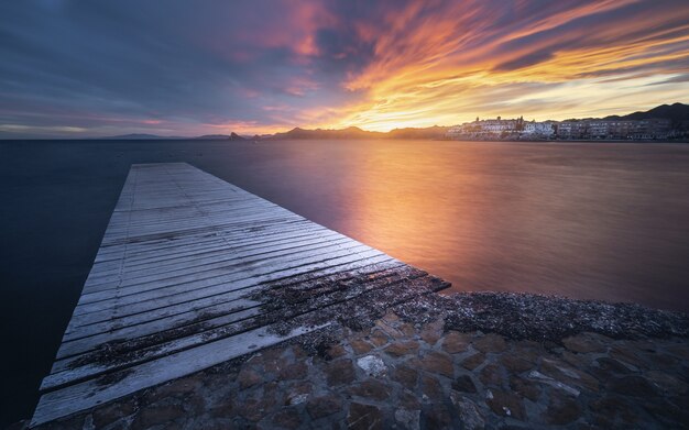 Impresionante vista del paisaje marino con un muelle de madera en la espectacular puesta de sol escénica