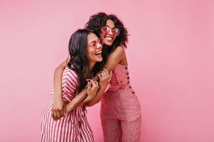 Foto gratuito increíble, bella dama se regocija y disfruta de la sesión de fotos en rosa. las niñas africanas con el pelo rizado en gafas de sol se ríen.