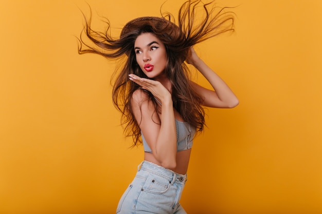 Increíble chica con cabello largo y liso bailando y enviando beso al aire