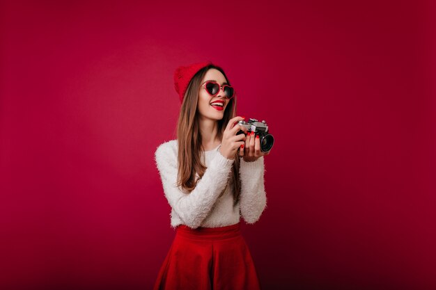 Increíble chica con elegante manicura roja posando con espacio clarete