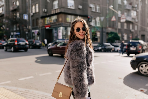 Increíble chica con maquillaje nude con elegante traje de otoño caminando en la ciudad soleada