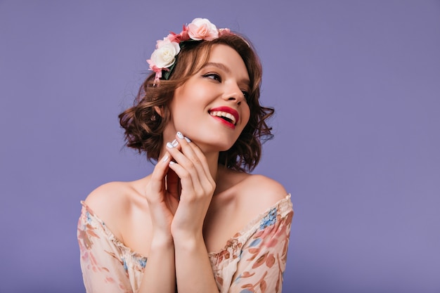 Increíble chica morena en traje de primavera posando con flores en la cabeza. sonriente mujer soñadora aislada.