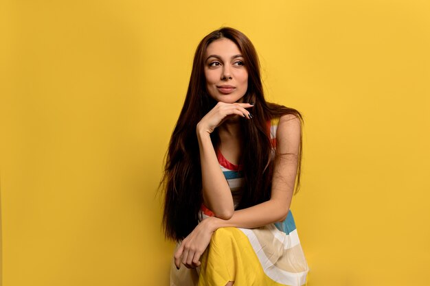 Increíble chica soñadora con cabello largo con vestido de verano posando.