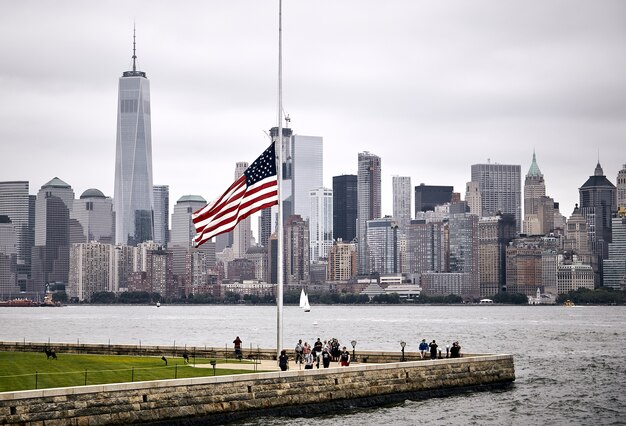 Increíble foto de la bandera estadounidense en un parque en el fondo del horizonte de Manhattan