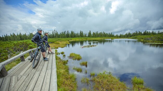 Increíble foto de dos ciclistas disfrutando de la vista del lago Ribnica en Eslovenia