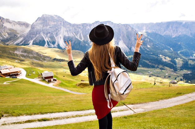 Foto gratuita increíble imagen de experiencia de viaje de hermosa mujer elegante posando de nuevo y mirando impresionantes vistas a las montañas