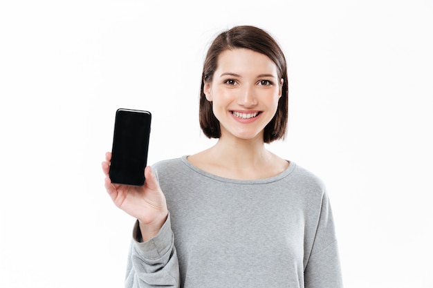 Increíble mujer caucásica joven mostrando la pantalla del teléfono.