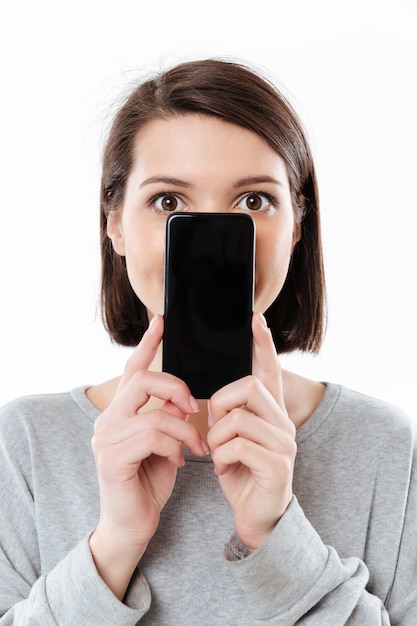 Increíble mujer caucásica joven mostrando la pantalla del teléfono.