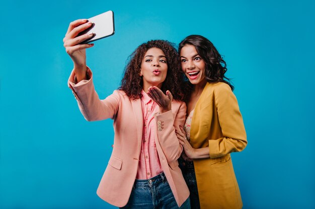 Increíble mujer de chaqueta amarilla posando mientras su amiga toma la foto