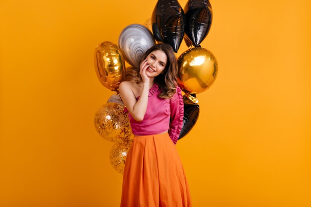 Increíble mujer de cumpleaños posando en la pared naranja