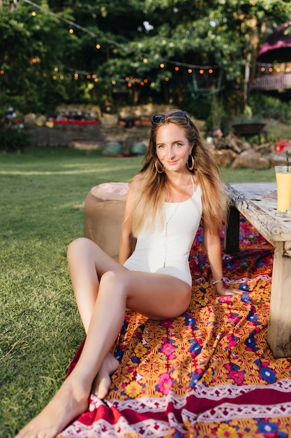 Increíble mujer descalza pasar tiempo en el parque. Disparo al aire libre de modelo femenino de pelo largo tomando el sol en las vacaciones de verano.