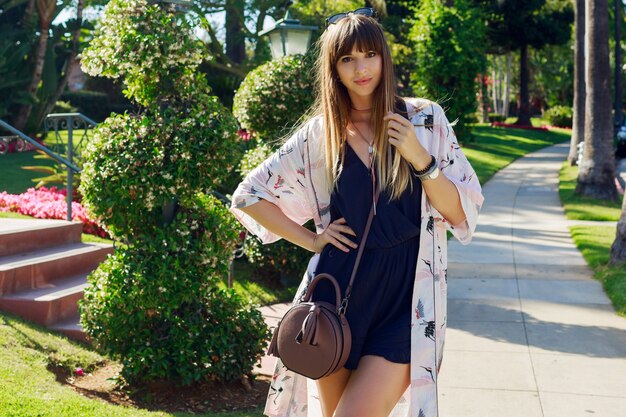 Increíble mujer elegante en mono azul y kimono blanco disfrutando de las vacaciones.