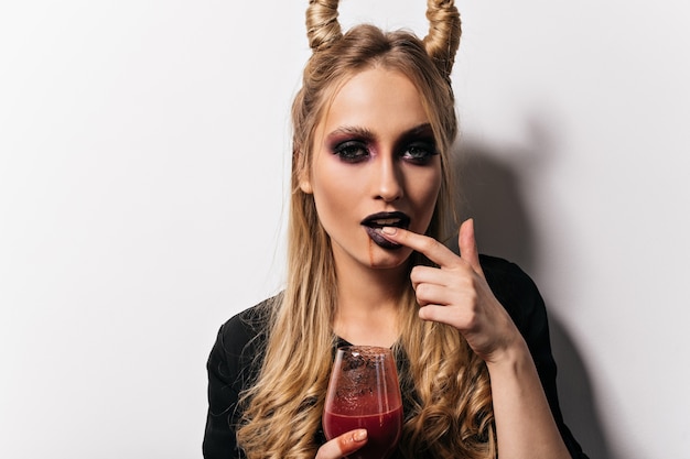 Increíble mujer rubia posando en la fiesta de halloween con sangre. vampiro encantador con maquillaje negro.