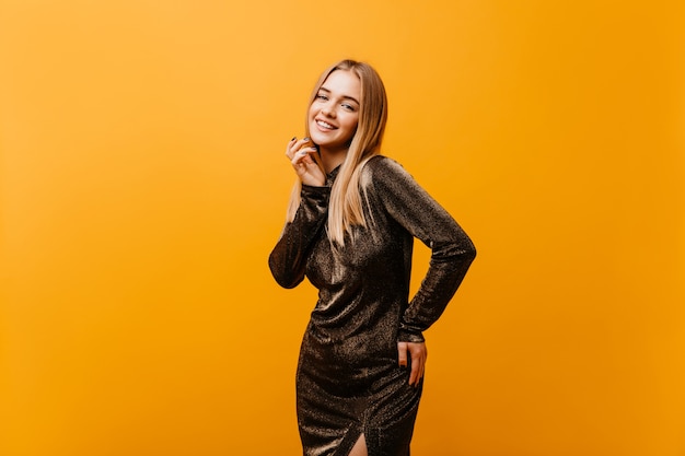 Increíble mujer rubia con vestido elegante sonriendo. Retrato de interior de hermosa modelo caucásica con expresión de cara feliz.