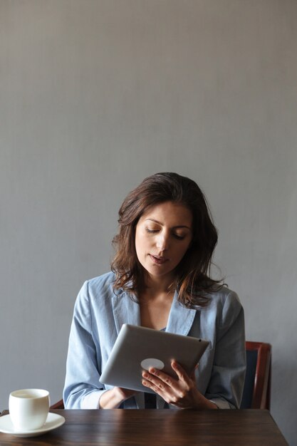 Increíble mujer sentada en el interior con tablet PC.