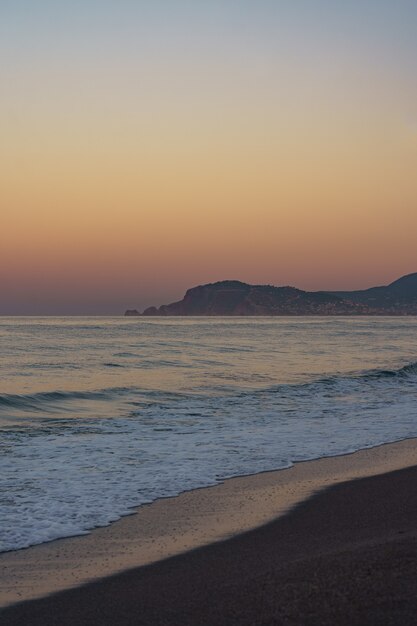 Increíble puesta de sol en la playa con horizonte infinito y figuras de montañas solitarias en la distancia