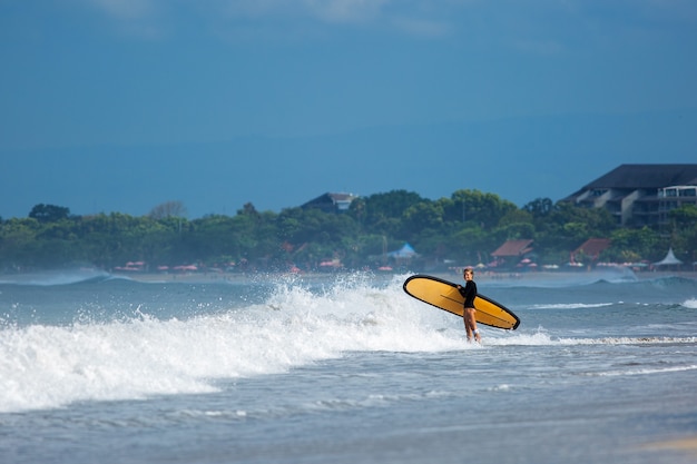 Foto gratuita increíble vista. hermosa niña se encuentra con una tabla de surf en la orilla del océano