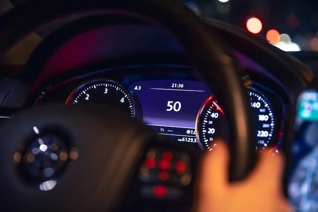 Indicación de velocidad y manos de la mujer en el volante de un coche por la noche