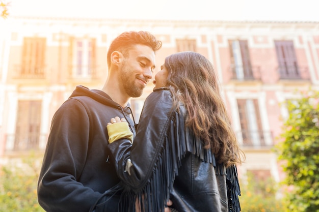 Individuo feliz joven que abraza a la señora cerca del edificio