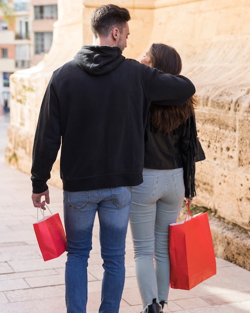 Foto gratuita individuo joven que abraza a la señora con el paquete en la calle