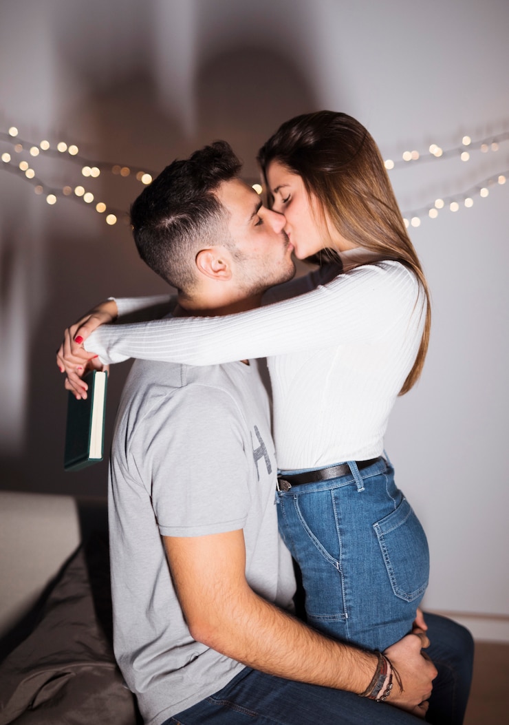 Foto gratuito individuo joven que besa y que abraza a la señora con el libro en el sofá