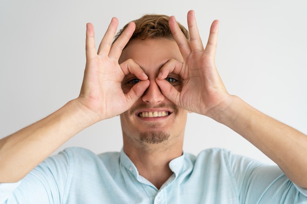 Individuo sonriente alegre que muestra gesto de los vidrios.