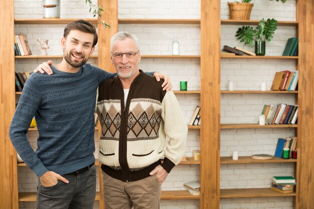 Individuo sonriente joven que abraza con el hombre feliz envejecido