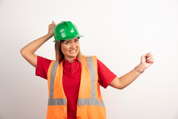 Foto gratuita industria de la mujer del trabajador del retrato que lleva el uniforme de seguridad que presenta de pie sobre fondo blanco.