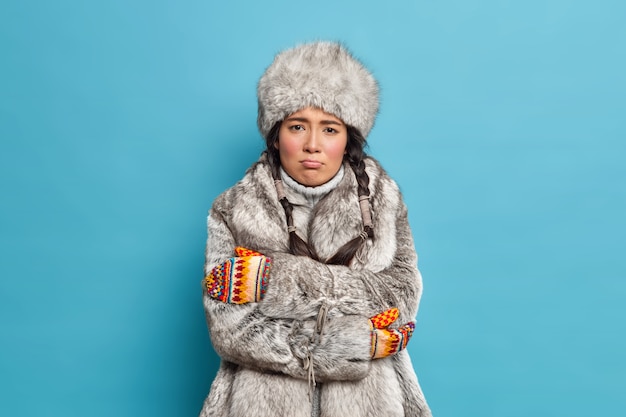 Foto gratuita infeliz mujer escandinava con sombrero de piel y abrigo cruza las manos y siente temblores de congelación durante el día helado severo usa ropa de abrigo de invierno