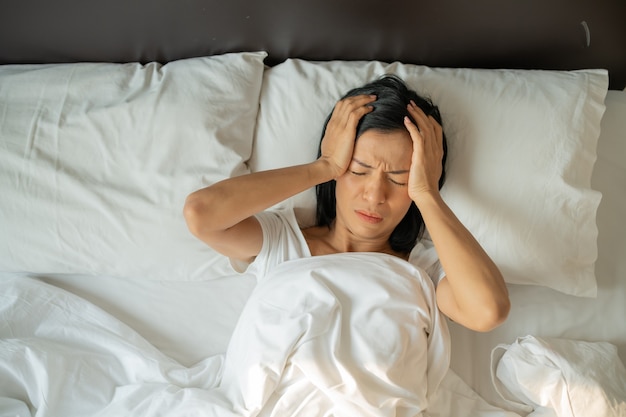 Foto gratuita infeliz mujer madura agotada con los ojos cerrados acostada en la cama, tocando las sienes de cerca, mujer cansada que sufre de dolor de cabeza o migraña, malestar, insomnio, falta de sueño