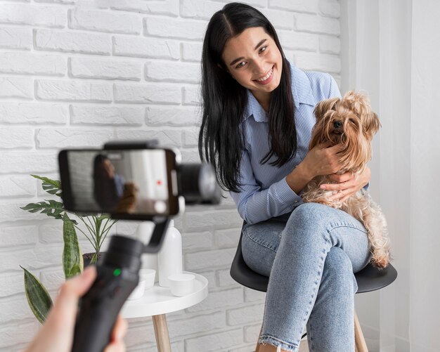 Influencer femenina en casa con mascota y smartphone