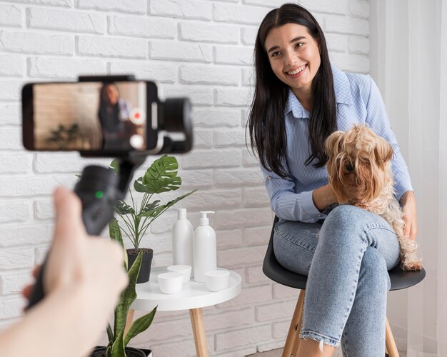 Influencer femenina en casa con perro y smartphone