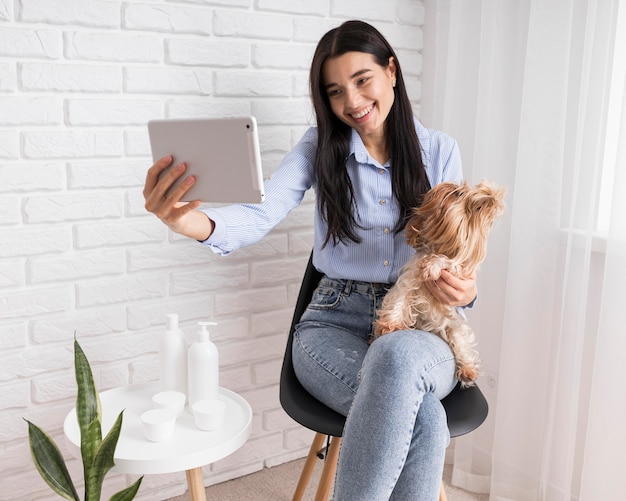 Foto gratuita influencer femenina en casa con tableta y perro