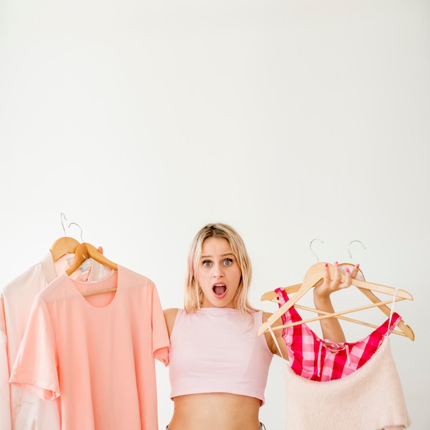 Foto gratuita influencer rubia sosteniendo ropa rosa