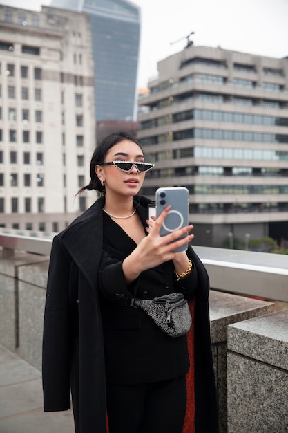 Foto gratuita influencer tomándose una selfie usando su teléfono inteligente en un puente