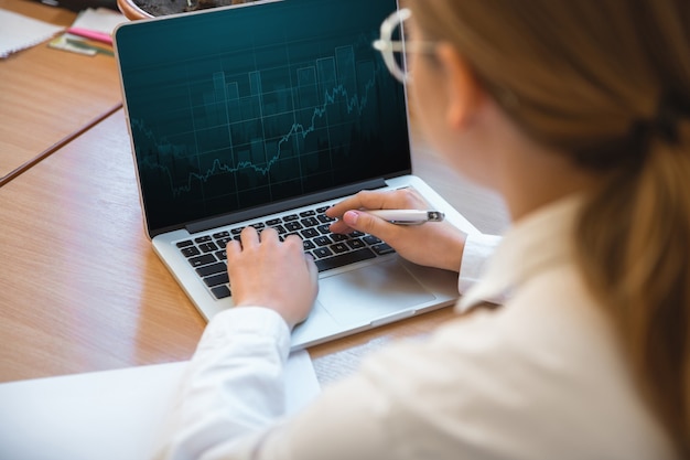 Foto gratuita informe de mecanografía. emprendedor caucásico, mujer de negocios, gerente que trabaja concentrado en la oficina. parece serio y ocupado, con atuendo clásico. concepto de trabajo, finanzas, negocios, éxito, liderazgo.